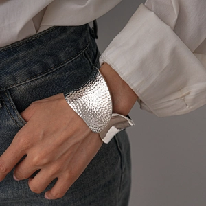 Detail of silver textured irregular bangle with hammered finish on model wrist