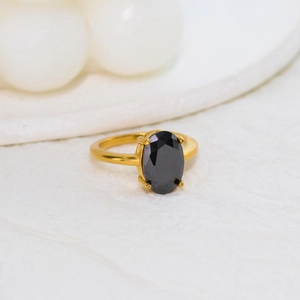 Macro view of gold stainless steel ring with a large oval black zircon in four-prong setting