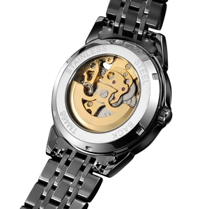 Close-up of the transparent case back showing the gold mechanical movement and steel band
