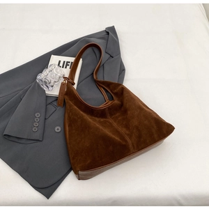 Detail shot of vintage dark brown suede tote bag on grey blazer for daily commute