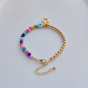 Detail of colorful beads, gold star charm, and evil eye bead on a boho bracelet