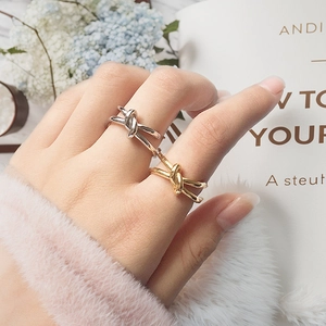 Detail shot of gold and silver knot rings on hands with stylish magazine backdrop