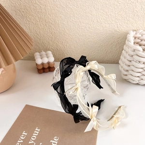 Detailed view of elegant chiffon bow headbands in black and cream on a glass