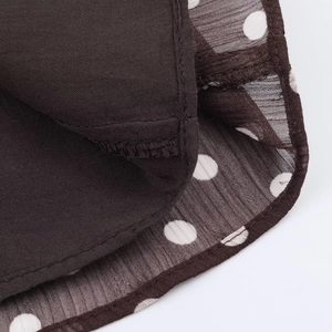 Close-up of brown double-layered hem with white polka dots on semi-transparent chiffon