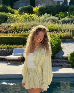 Detail of yellow and white striped resort wear shirt and shorts set on model in garden