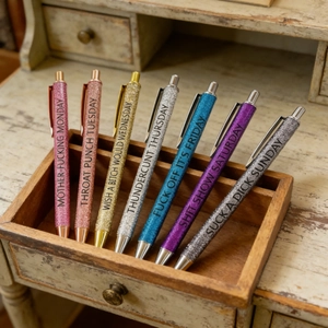 7pcs funny glitter ballpoint pens set with weekday phrases on a wooden desk organizer