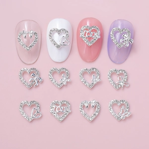 Silver alloy heart nail art charms with bow and crystals on soft pink background