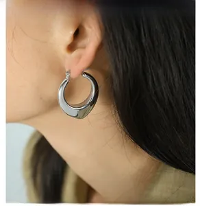 Side view of a silver-colored thick teardrop hoop earring worn by a model