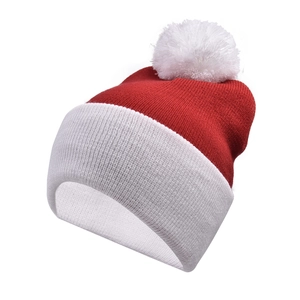 Detail of red and white knit Christmas hat featuring soft texture and white pompom