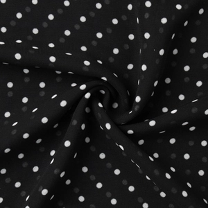 Close-up of black and white polka dot chiffon fabric with soft drape and light texture