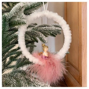 Detail of plush angel Christmas ornament hanging on tree with soft feathers and pink tones
