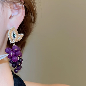 Gros plan d'élégantes boucles d'oreilles grappes violettes avec diamants scintillants