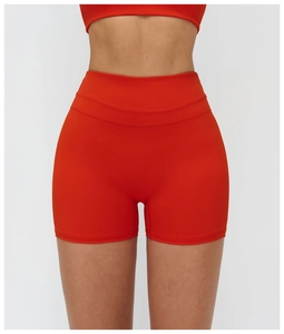 Détail macro du short de yoga extensible à taille haute rouge orangé avec coutures