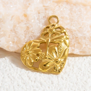 Elegant gold hollow heart pendant with floral daisy pattern on natural white stone background