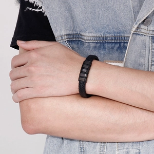 Gros plan d'un bracelet en cuir tressé noir avec détails métalliques au poignet d'un homme