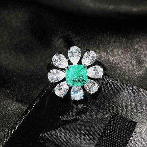 Detailed close-up of emerald cut gemstone ring with radiant floral halo on black silk