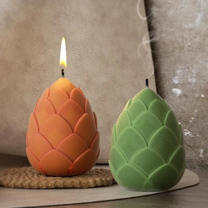 Artistic artichoke shaped pine cone candles in green and orange with matte texture