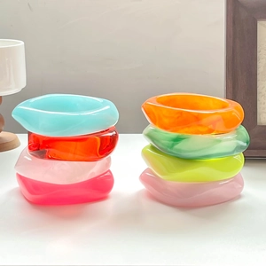 Chic irregular thick resin bangles set in vibrant colors on a minimalist white stand
