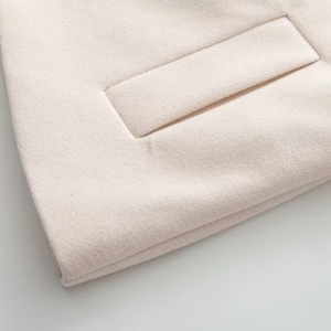 Détail macro du tissu en laine beige du manteau et de la couture de la poche plaquée
