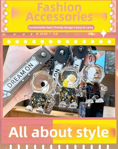 Close-up of black and gold astronaut drifting bottle keychain with sparkling glitter stars