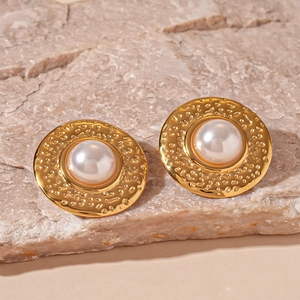 Detail of vintage gold round earrings featuring hammered metal texture and center pearl