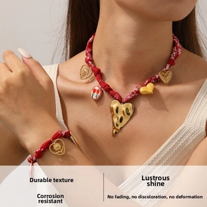 Detail of red floral fabric rope necklace and bracelet set with golden heart pendants
