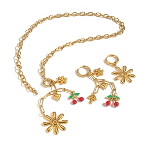 Elegant 18K gold necklace and earring set featuring floral and cherry fruit charms on white