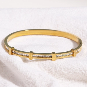 Vue détaillée du bracelet en acier titane doré avec zircone carrée sur tissu blanc