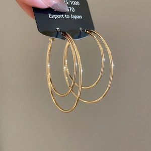 Detailed view of hand-held double-layered gold hoop earrings with S925 silver needles