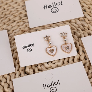 Golden heart earrings with crown design and white rhinestones on display card