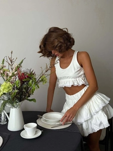 White two-piece set with sleeveless ruffle crop top and lace-trimmed tiered mini cake skirt