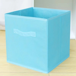Foldable light blue non-woven storage box with handle on wooden floor, 45-degree view