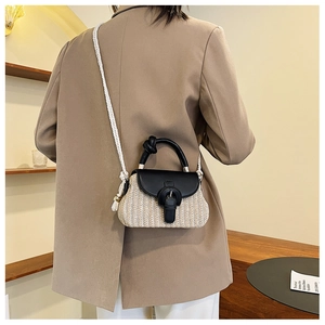 Detail of woven straw bag with black leather flap and stylish thick rope shoulder strap
