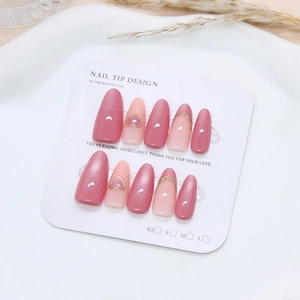 Handmade cat-eye press-on nails with golden hearts and French tips on a ceramic plate