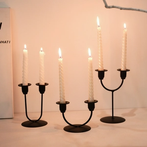 Nordic minimalist black iron candle holder with burning white spiral candles on table
