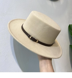 Detail of beige flat top wool fedora hat featuring a dark brown leather buckle band