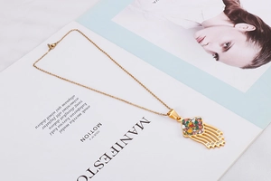 Detail of gold fan pendant necklace with colorful enamel inlay and fringe tassels