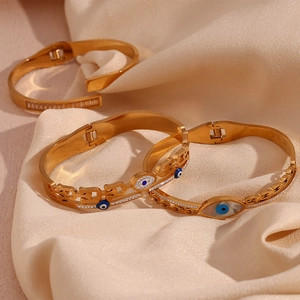 Macro detail of 18K gold-plated evil eye bracelets with pavé zircons on satin background