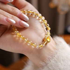 Close-up of Citrine beaded bracelet with a gold heart pendant on a woman's wrist