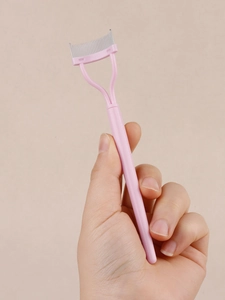 Macro detail of pink steel-tooth eyelash comb for separating lashes after mascara