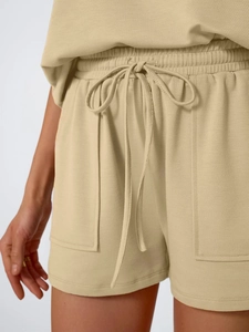 Detail view of khaki knit shorts with elastic drawstring waist and side patch pockets