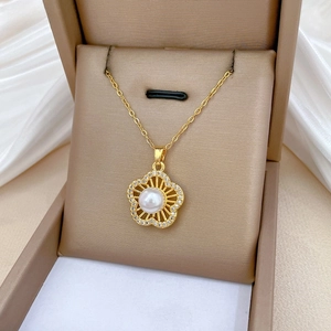 Close-up of golden clover necklace with central pearl and pavé crystals in a jewelry box