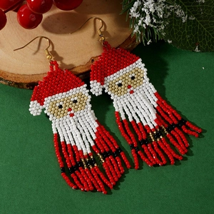 Orecchini a cerchio con Babbo Natale in perline e nappe su sfondo festivo di pino e bacche