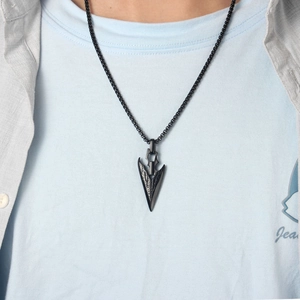 Detail of a vintage black arrowhead pendant on a bead chain necklace worn by a male model