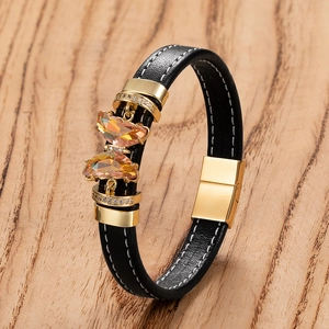 Détail du bracelet en cuir noir avec cristaux papillon orange et coutures blanches