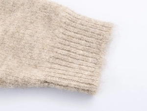 Dettaglio del cardigan in maglia beige con polsini a coste e morbida consistenza pelosa