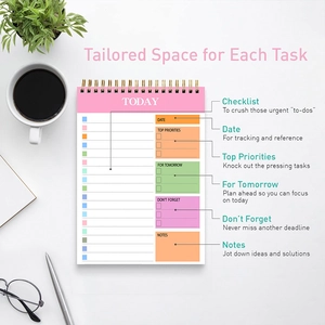 Flat lay of pink spiral daily planner on marble background with office accessories