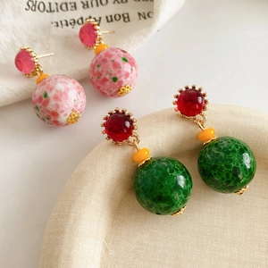 Détail de boucles d'oreilles vintage en céramique avec motifs mouchetés rouges et verts