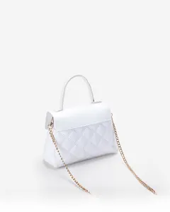 Detail of white quilted handbag with gold chain strap and fine stitching texture