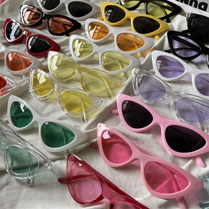 Close-up of stylish cat eye sunglasses in various candy colors on a white fabric backdrop